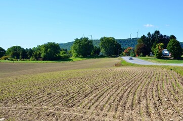 Rural landscape in New York State. Farmland - plowed field with row pattern, road and mountainS