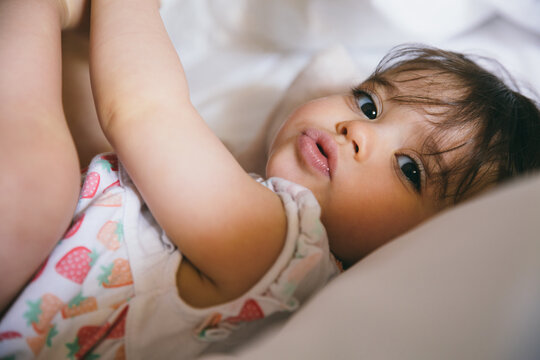 Duckface of a cute baby girl lying on a bed