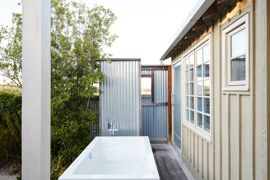 Outdoor bathroom with tub and shower on patio of cottage