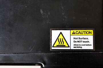 A caution label sticker applied on a metal oven surface, warning users to avoid touching the hot...