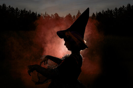 A silhouette of young girl in a witch costume