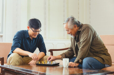 Senior asian father and middle aged son playing chess game in living room, Happiness Asian family concepts