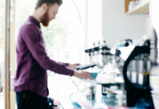Out of focus man making coffee in a cafe.