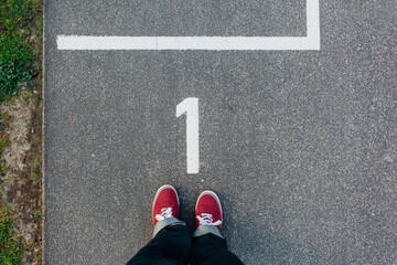 Red sneakers on starting line number 1, footsie, personal perspective