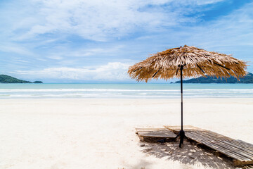 Beach Umbrella made of palm leafs on a perfect white beach in front of Sea.