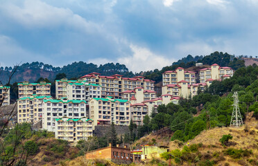 Obraz premium wide shot of buildings along side hills and cloudy blue sky in the background