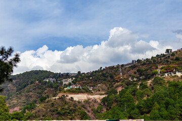 Fototapeta na wymiar wide view of a mountain with residential properties shot from low angle under the cloudy blue sky