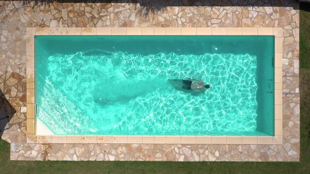 Aerial top shot view of young male adult jumping swimming pool in tuscany italy shot in 4k