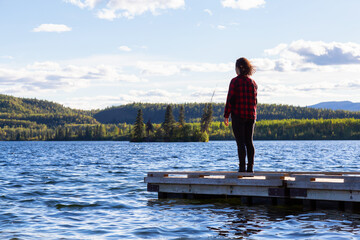 Adventurous Girl on a Wooden Quay at Twin Lakes Campground during a sunny summer day. North of Whitehorse, Yukon, Canada. Concept: travel, adventure, freedom