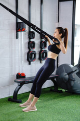 Fototapeta premium Asian woman in black exercise clothes Pulling the rope in the gym