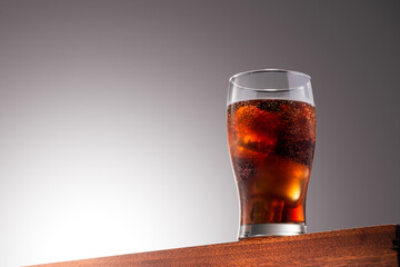 Cola glass with ice cubes on a Wooden Surface With Gradient Background