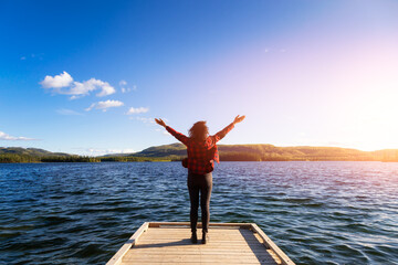 Adventurous Girl on a Wooden Quay at Twin Lakes Campground during a sunny summer. Sunset Colors. North of Whitehorse, Yukon, Canada. Concept: travel, adventure, freedom