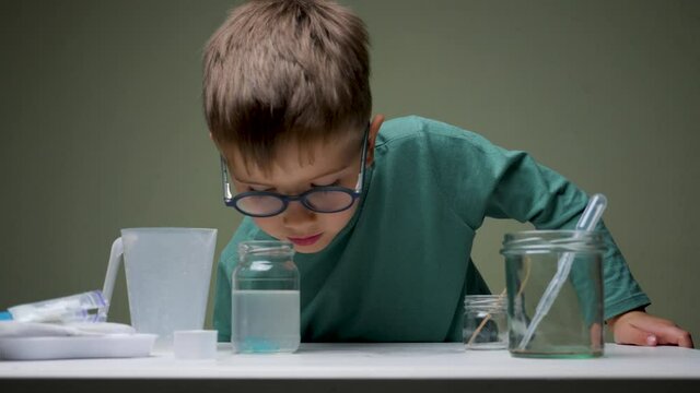 Boy in glasses does chemical experiment with pipette and liquid indoor. Studying, learning with interest. Alternative education. Research background. Personal qualities for successful studying