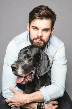 Handsome man looking at camera nad hugging his big dog