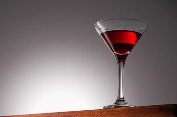 Red Drink in Martini Glass on a Wooden Surface With Gradient Background