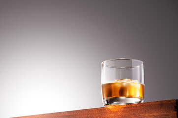 Glass of whiskey on the rocks on a Wooden Surface With Gradient Background