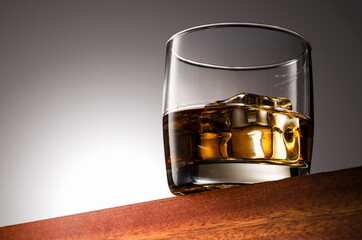 Glass of whiskey on the rocks on a Wooden Surface With Gradient Background