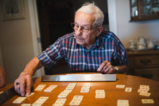 Senior man playing game of rummy at table inside
