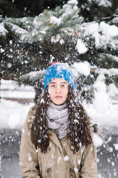Young woman wearing winter clothes standing under falling snowflakes