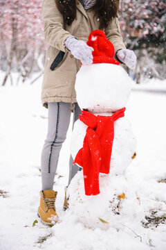 Young woman standing behind a snowman