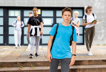 Focused teenager walking outside college building in autumn day, going to lessons.