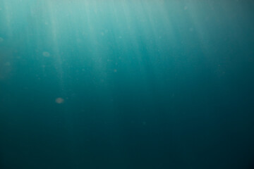 Dark blue under water empty sea background with sunrays going trough the surface