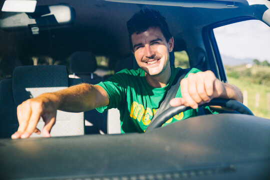 Front view from the outside of young man driver inside van during a road trip on a sunny day