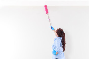 Asian woman uses a pink microfiber duster to clean her ceiling.