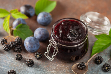 Blackberry and plum jam preserves  in a jar and fresh berries on the table.