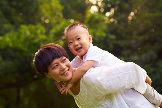 happy little asian boy with her mother outdoor in the summer park