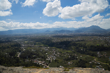 Beautiful landscape of a small town seen from the top of the mountain - rural town surrounded by trees, mountains and a volcano on a sunny day with clouds - landscape in Quetzaltenango 