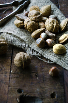 Mixed shell nuts on a piece of burlap on a wooden background.