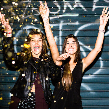 Smiling women throw confetti