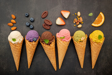 Various of ice cream flavor in cones blueberry ,pistachio ,almond ,orange and chocolate setup on dark stone background . Summer and Sweet menu concept.