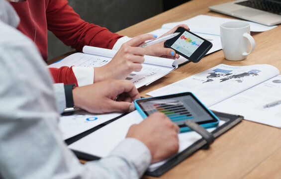 Coworkers comparing colorful statistical graphs using smart devices