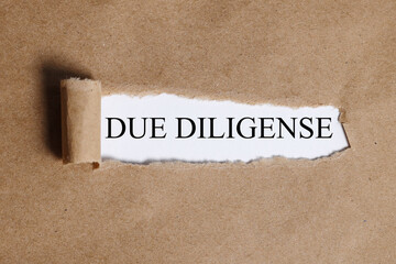 due diligense. Text on white paper on torn paper