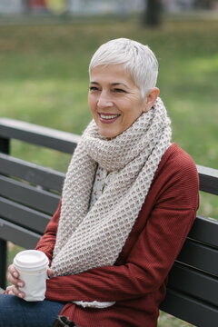 Smiling Senior Woman Sitting On The Park Bench