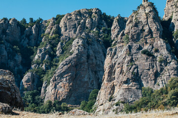 Ridge of brown rocks covered with greenery against a blue sky