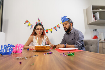 Pareja de novios festejando en casa cumpleaños con pastel