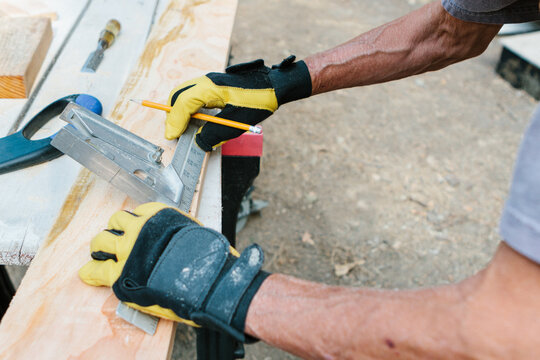 Elderly woman carpenter measuring lumber with a square