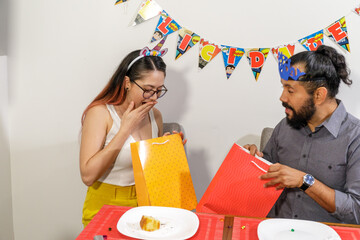 Pareja de jovenes mexicanos novios recien casados intercambian regalos durante cumpleaños en casa