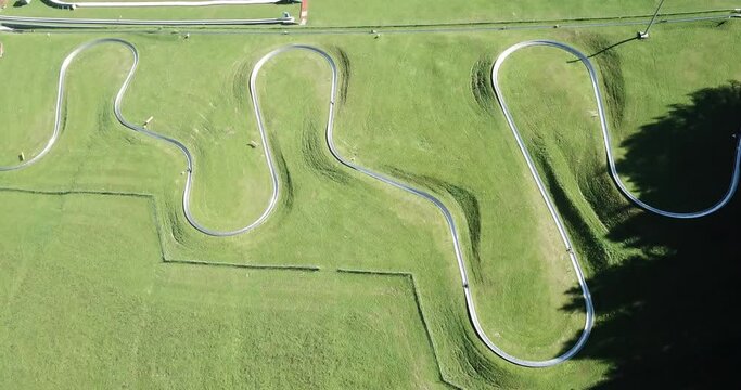 Amazing drone aerial view of a summer bobsleigh track. Passo della Presolana. Bergamo, Italy. Natural contest. Leisure time. Beautiful nature with green meadow. Vertical landscape