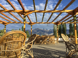 Outdoor dining on a deck overlooking mountains under a bamboo pergola.