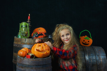 Portrait of a little girl in the Studio with pumpkins on a dark background . Halloween party