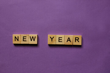 Words New Year. Wooden blocks with inscription on purple background. The bulletin board. Concept of...