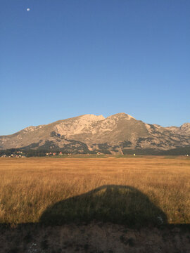 Shadow of a car with two people traveling trough Montenegro at sunrise