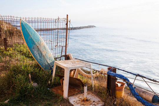 Old school surfboard and other stuff standing on a cliff, with the Atlantic Ocean in the background
