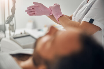 Cosmetologist putting on sterile gloves before cosmetic procedure