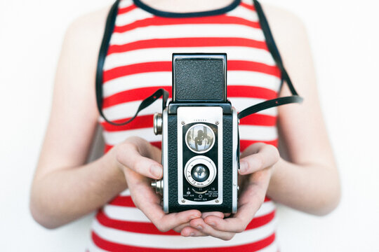 Child in stripes holding a vintage camera