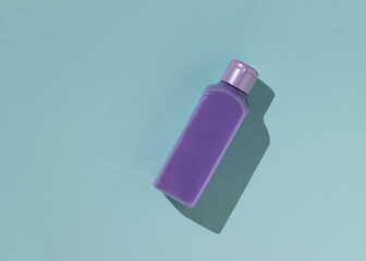 Purple plastic bottle with cosmetics on a blue background.